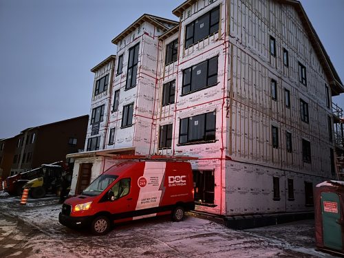 Immeuble à logements en structure enveloppée avec fourgon Doc Électrique, au crépuscule