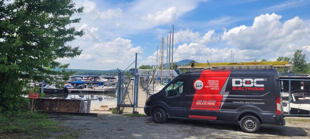 Fourgon Doc Électrique stationné près d'une marina commerciale avec bateaux
