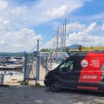 Fourgon Doc Électrique stationné près d'une marina commerciale avec bateaux